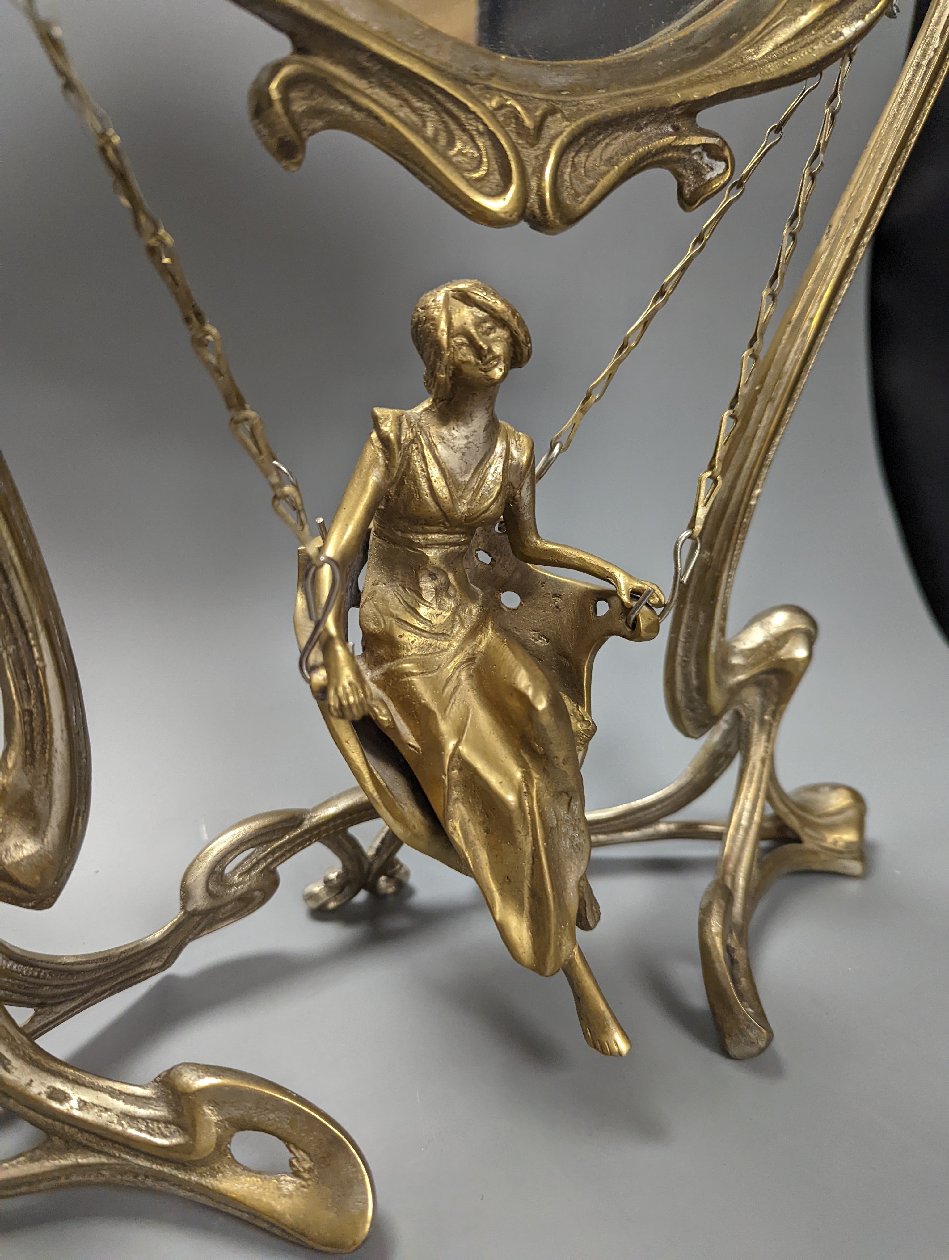 An Art Nouveau style mirror with model of girl sitting on a swing, height 45cm